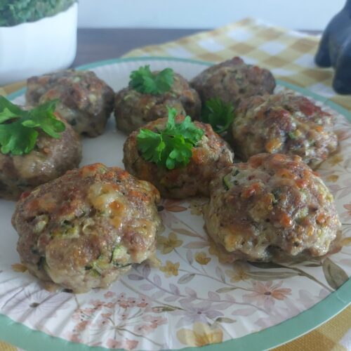 Upečené karbanátky z krůtího masa s cuketou a mozzarellou na talíři, ozdobené petrželkou