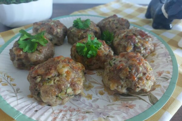 Upečené karbanátky z krůtího masa s cuketou a mozzarellou na talíři, ozdobené petrželkou